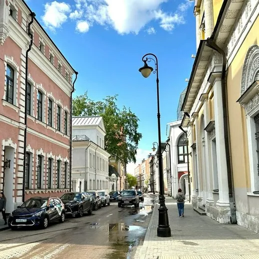 Узкая улица в центре города с историческими зданиями и светлым небом, после дождя