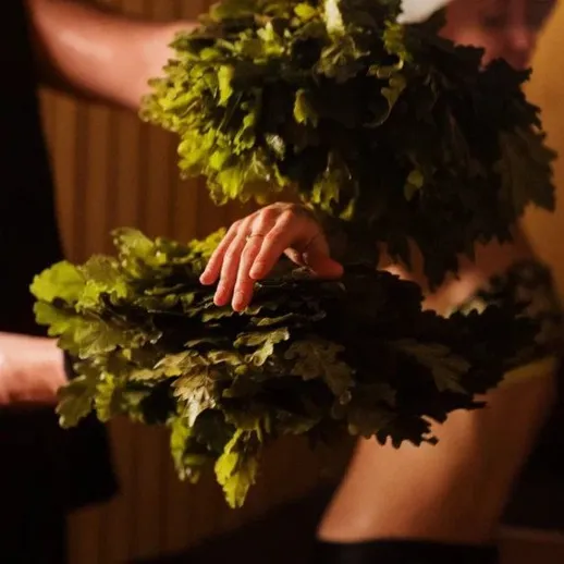 Человек с вениками готовится к бане и оздоровительным процедурам в спа