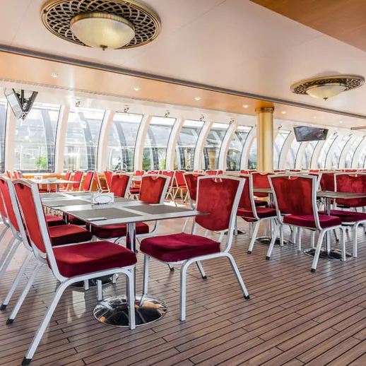 Освещенное кафе с красными стульями на палубе судна в солнечный день
