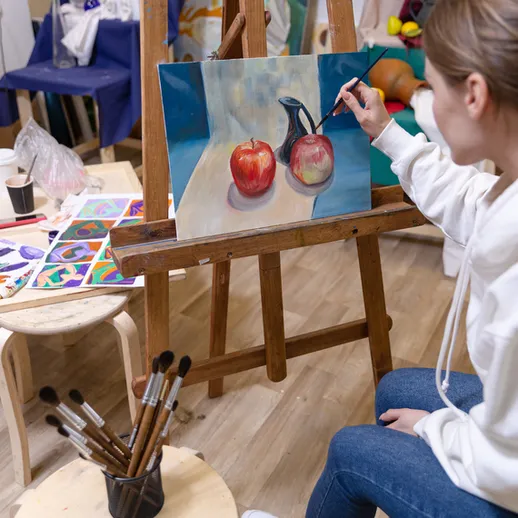 Художник создает натюрморт с яблоками в студии во время занятия живописью