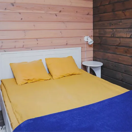 Уютная спальня с кроватью и яркими подушками в деревянном загородном доме