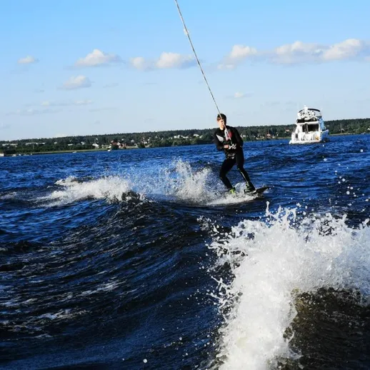 Каскадер на водных лыжах выполняет трюки на озере в солнечный день