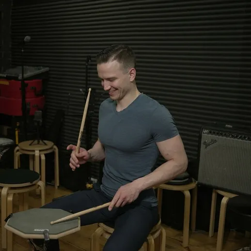 Мужчина играет на тренировочной установке для барабанов в музыкальной студии