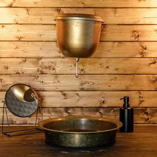 Уютный интерьер ванной комнаты с медной раковиной и деревянными стенами в загородном доме