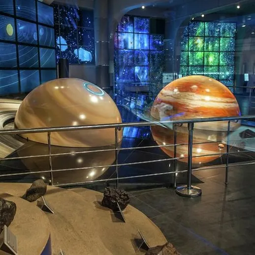 Экспозиция планет в научном музее, где представлены модели Юпитера, Сатурна и других небесных тел в вечернее время