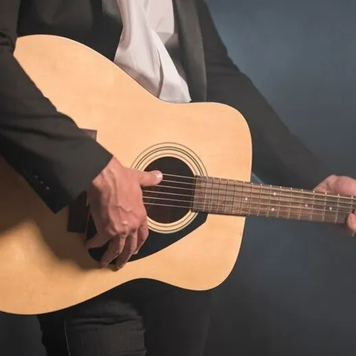 Игра на акустической гитаре в тёмном помещении во время вечернего концерта