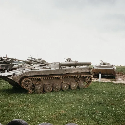Танк на военной базе, окруженный небо и зеленью, в тумане раннего утра