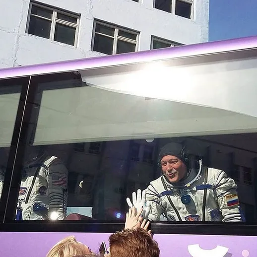 Астронавт улыбается прохожим в автобусе во время экскурсии