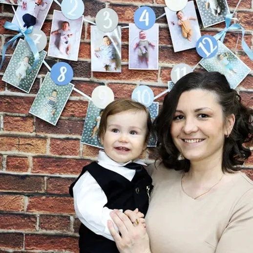 Мать с ребёнком на фоне фотогалереи, посвящённой первому году жизни ребёнка