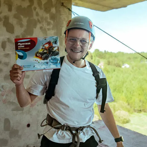 Человек в каске на стройплощадке показывает заслуженный сертификат после успешного альпинистского восхождения