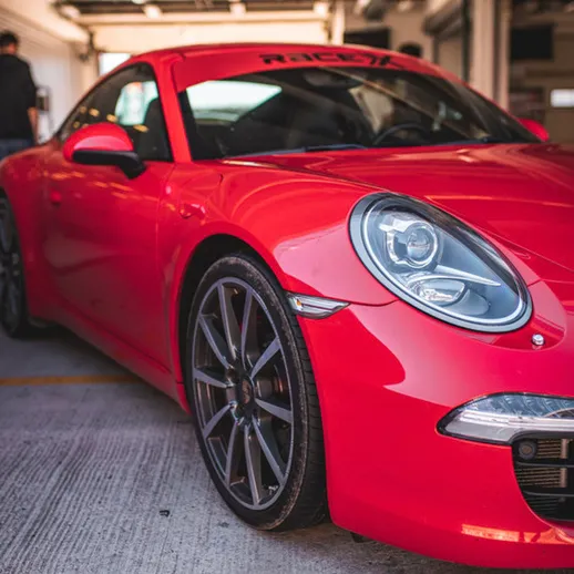 Яркий красный спортивный автомобиль на гоночной трассе в солнечный день