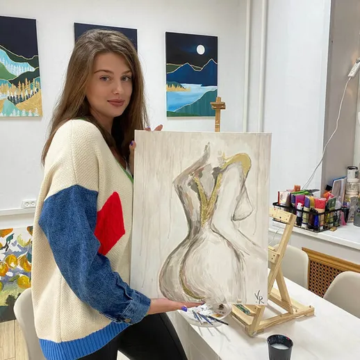 Художница демонстрирует свою работу на художественном занятии в студии в вечернее время