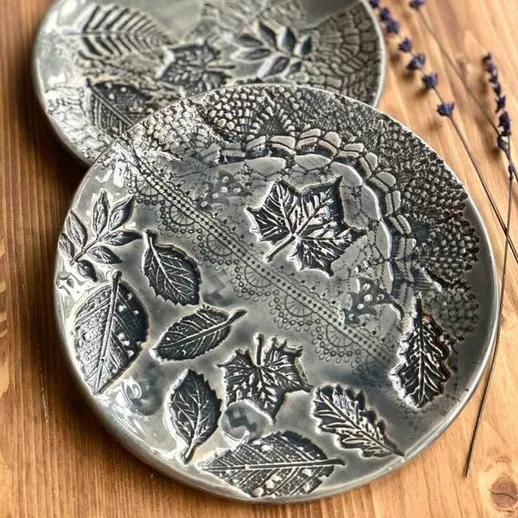 Красивые керамические тарелки с рельефным рисунком листьев на деревянном столе