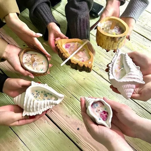 Люди держат свечи на деревянном столе во время встречи на свежем воздухе