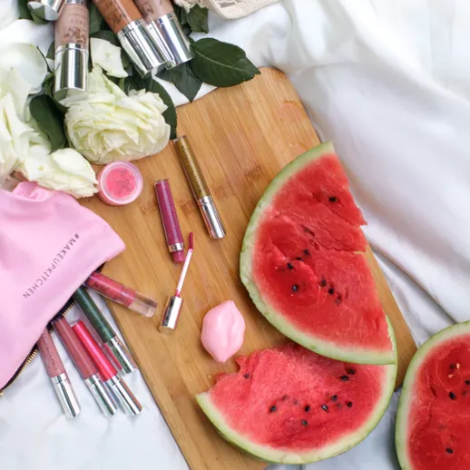 На столе лежат арбузы, косметические средства и цветы на белом фоне