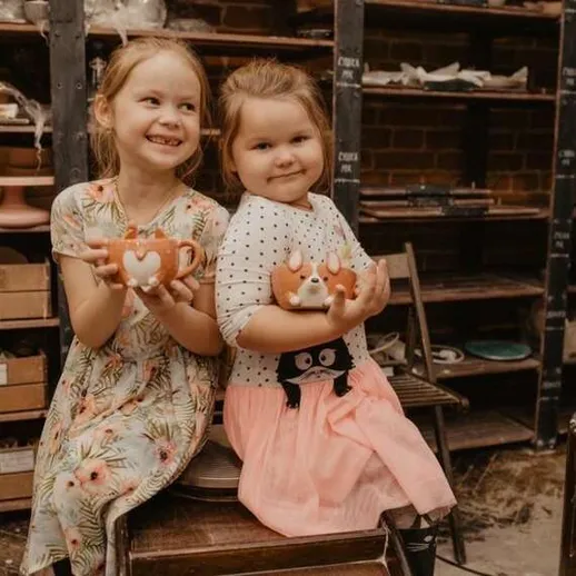 Две девочки радуются своей керамической посуде в мастерской гончарного искусства