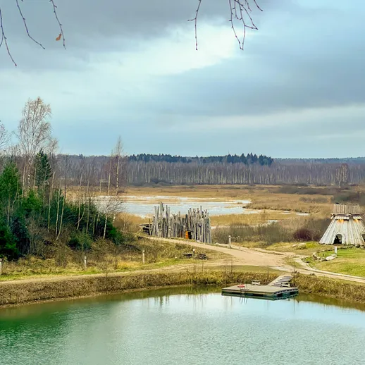 У tranquil lake with wooden structures and forested landscape in late autumn near a rural area in Russia