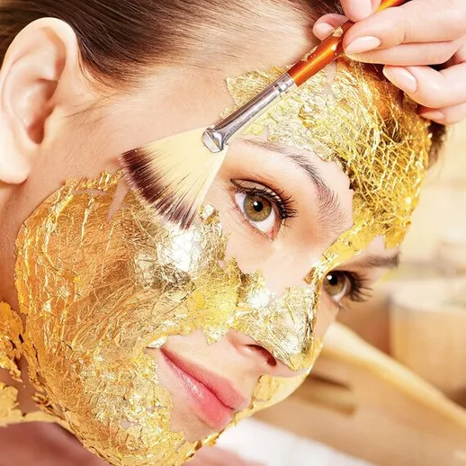 Женщина с золотой маской на лице получает косметическую процедуру в уютном салоне красоты