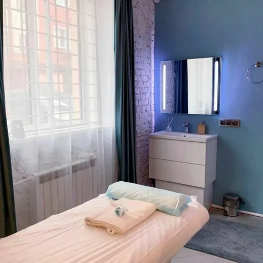 Уютный массажный кабинет в современном интерьере с окном и комфортной массажной кушеткой