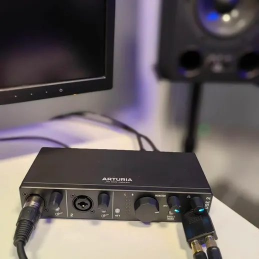 Аудиоинтерфейс Arturia на столе в студии звукозаписи с подключением к мониторам