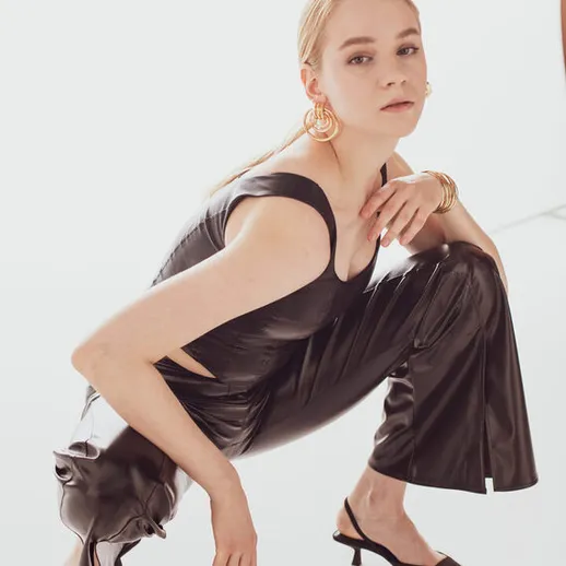 Модель в стильном наряде позирует на фоне с мягким светом и создает выразительный образ