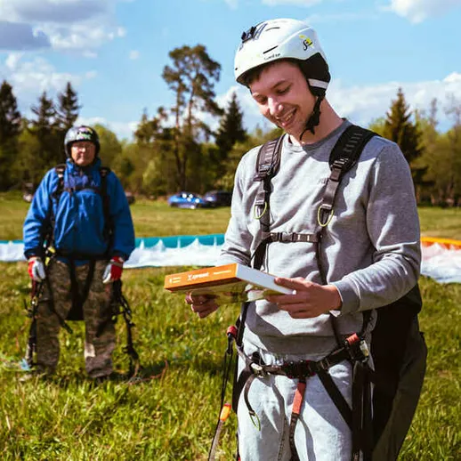 Молодой парапланерист читает инструкции по безопасности на тренировке в солнечное время у подножия гор