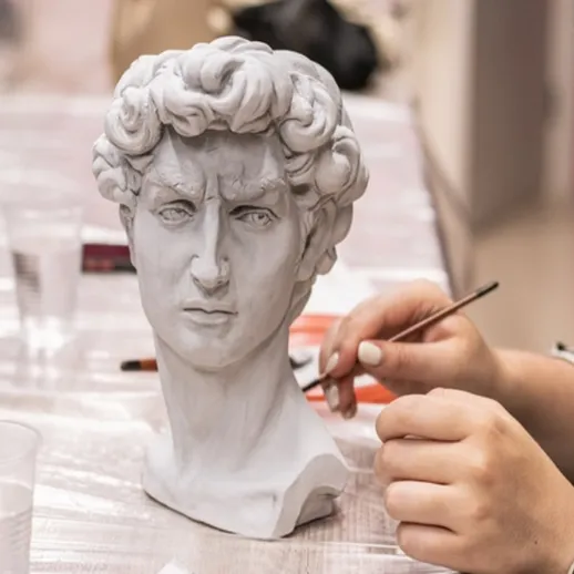 Скульптор работает над бюстом Давида в мастерской во время художественного курса
