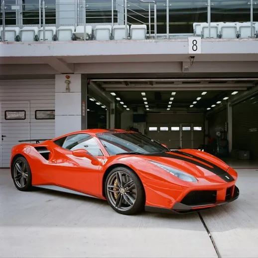 Красный спортивный автомобиль на гоночной трассе в солнечный день