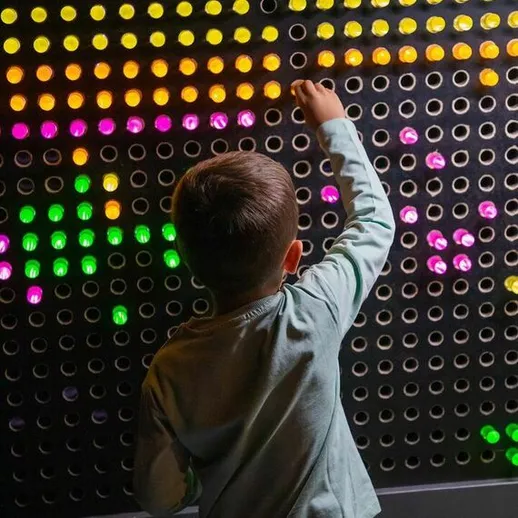 Мальчик играет с интерактивной стеной в развлекательном центре в вечернее время