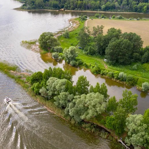 Пейзаж реки с зелеными берегами и лодкой на воде, снятый в солнечный день