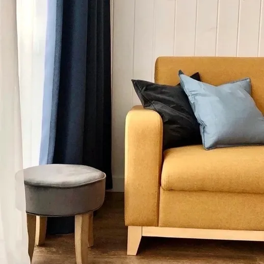 Стильный уголок гостиной с желтым диваном и уютным пуфом в современном интерьере