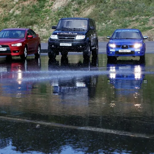 Три автомобиля на водной поверхности во время тренировки по управлению в сложных условиях