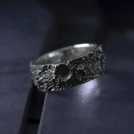 Уникальное кольцо с текстурой, выполненное из металла, на темной поверхности, выполненное вручную в современном стиле
