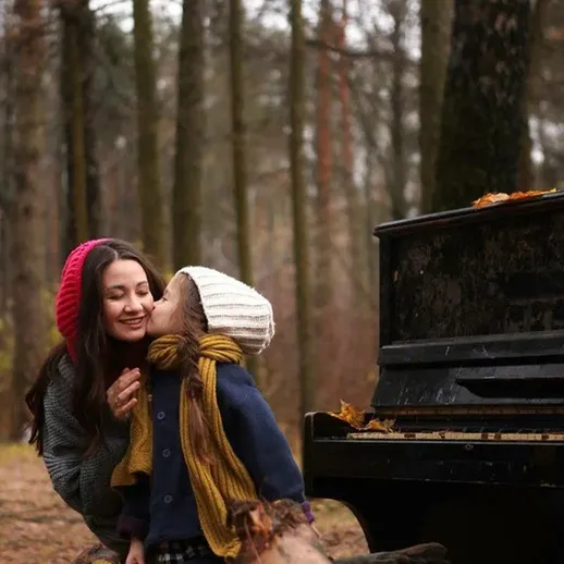 Мать и ребенок играют у пианино на природе осенью в лесу