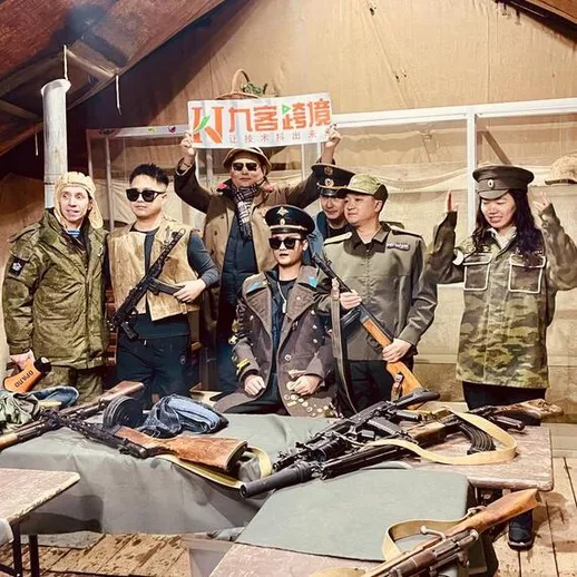 Группа людей в военной форме позирует с оружием в помещении с деревянным полом