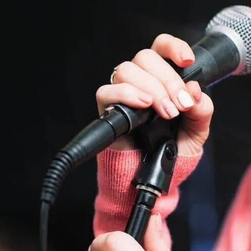 Момент исполнения песни на сцене с использованием микрофона в уютной атмосфере