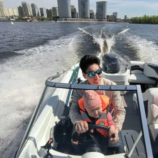 Отец управляет лодкой с ребенком на реке в городе