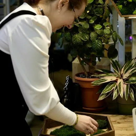 Женщина работает над зелеными растениями в уютном пространстве с растениями в центре города