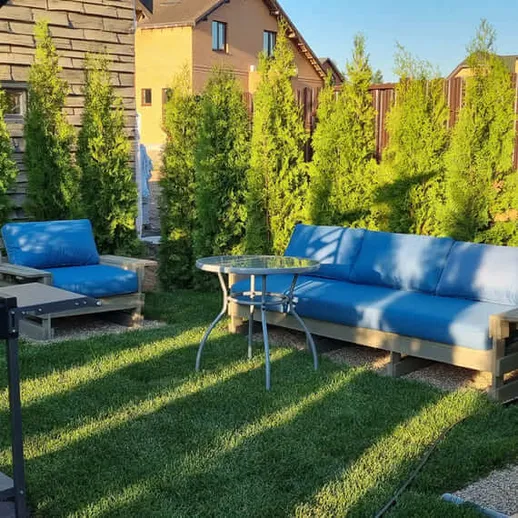 Уютный сад с зоной отдыха, качелями и мангалом на заднем дворе в солнечный день