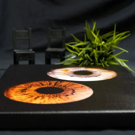 Картина с изображением глаз на черном фоне и два стульчика рядом с ней