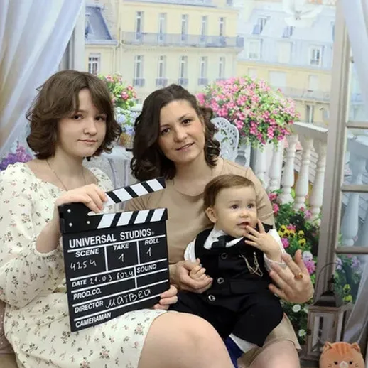 Мать с ребенком и подростком на фоне декораций с киносъемками в домашней обстановке