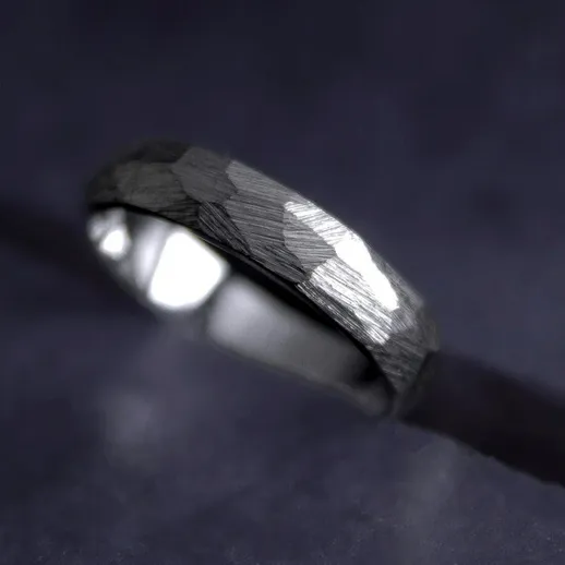 Изящное кольцо из серебра на черной поверхности с отражениями света и текстурой, подчеркивающей его уникальность
