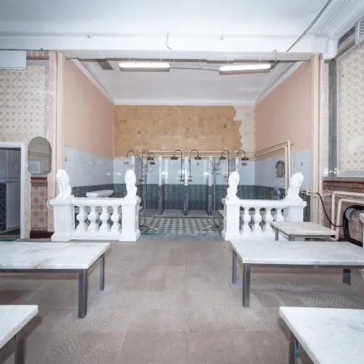 Классическая баня с мраморными столами и душевыми, расположенная в историческом здании, обладающая уникальным интерьером