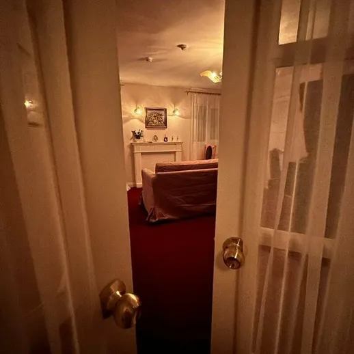 Уютная комната с камином и мягким освещением, вид из коридора, вечернее время