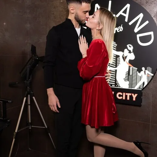 Романтический момент между парой на фоне логотипа заведения в вечернее время