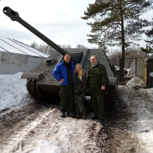 Семья на фоне танка в зимнем лесу, на фоне снега и деревьев, с улыбками на лицах, в солнечный день