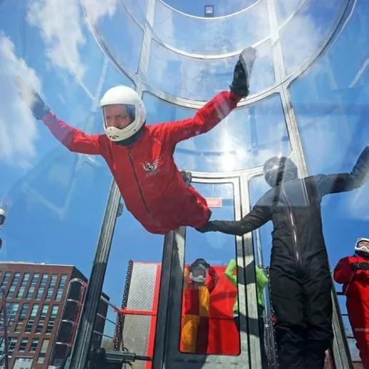 Люди наслаждаются интуитивным полетом в аэродинамической трубе в центре города в солнечный день