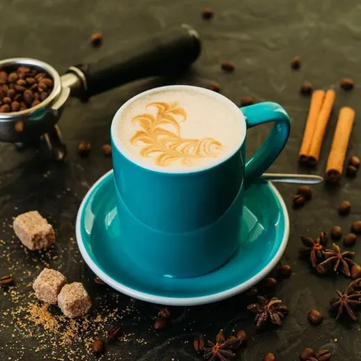 Чашка кофе с узором на пенке и кофейные зерна на столе