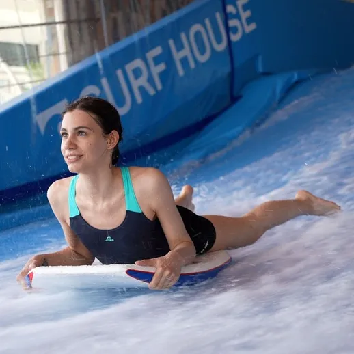 Женщина катается на сёрфе в крытом ландшафтном парке, наслаждаясь волнением на доске в Surf House