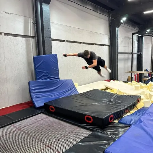 Прыжок акробата на батуте в зале для спортивной гимнастики